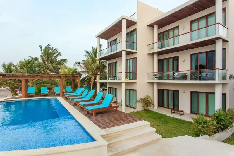 Bâtiment moderne avec piscine et transats, végétation tropicale environnante