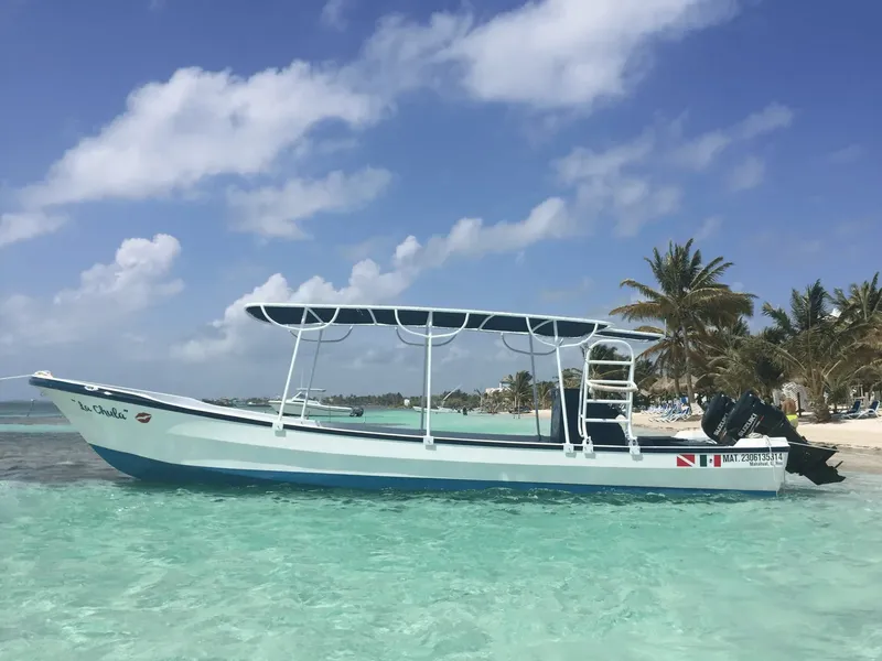 Bateau blanc et bleu amarré dans une eau turquoise peu profonde