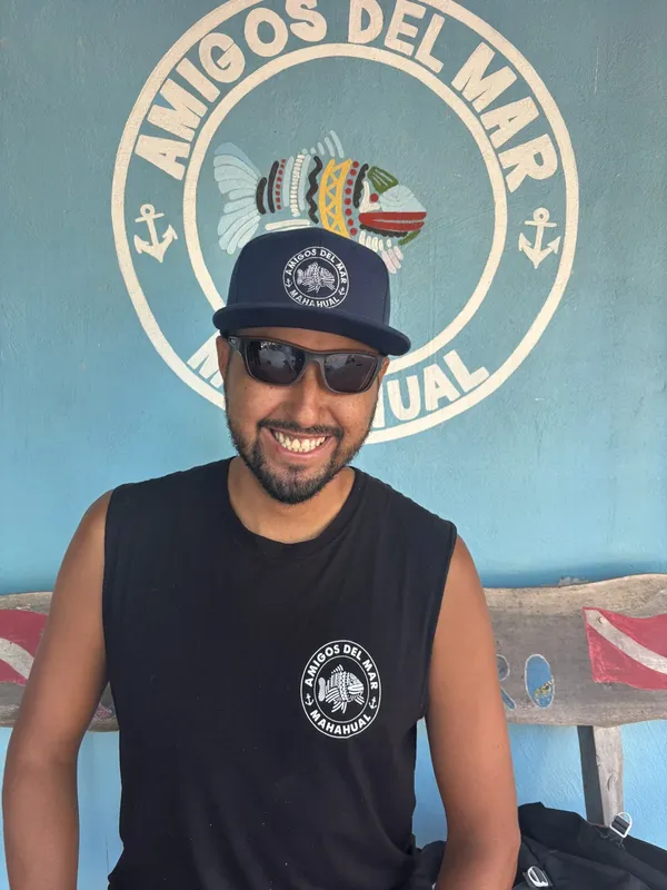 Homme souriant portant un débardeur et une casquette avec un logo