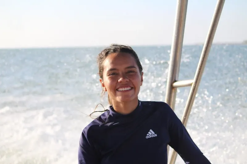 Jeune femme souriante sur un bateau avec l'océan en arrière-plan