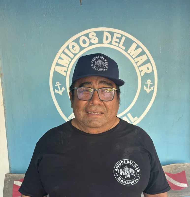 Portrait d'un homme souriant portant un chapeau avec un logo marin