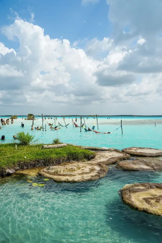 Personnes se relaxent dans des hamacs au milieu d'une eau turquoise claire
