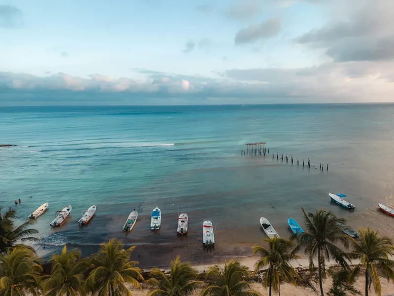 Plage tropicale avec plusieurs bateaux de pêche alignés sur le sable