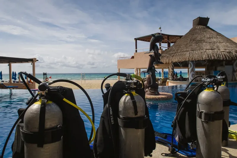 Bouteilles de plongée devant une piscine et un abri de plage