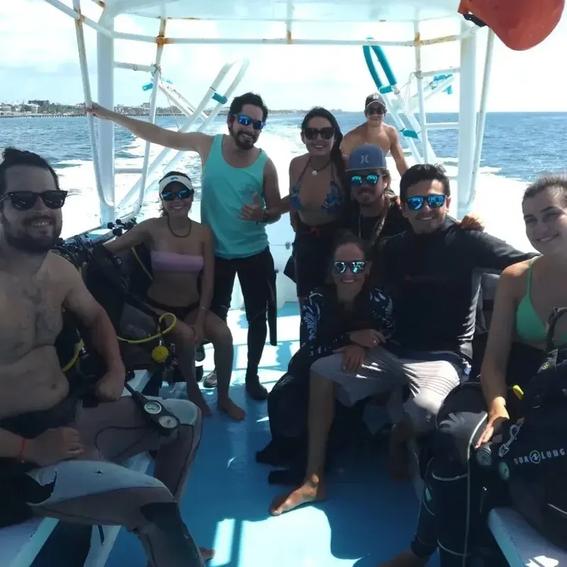 Groupe de plongeurs souriants sur un bateau en mer, équipés