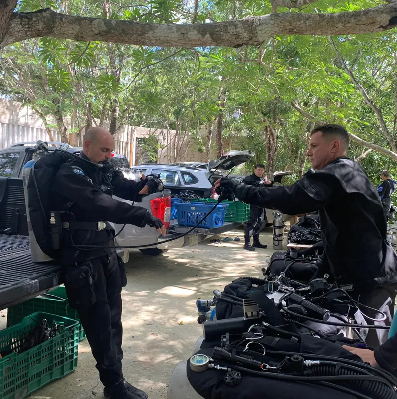 Deux plongeurs s'équipent avec des bouteilles et des détendeurs sur un parking