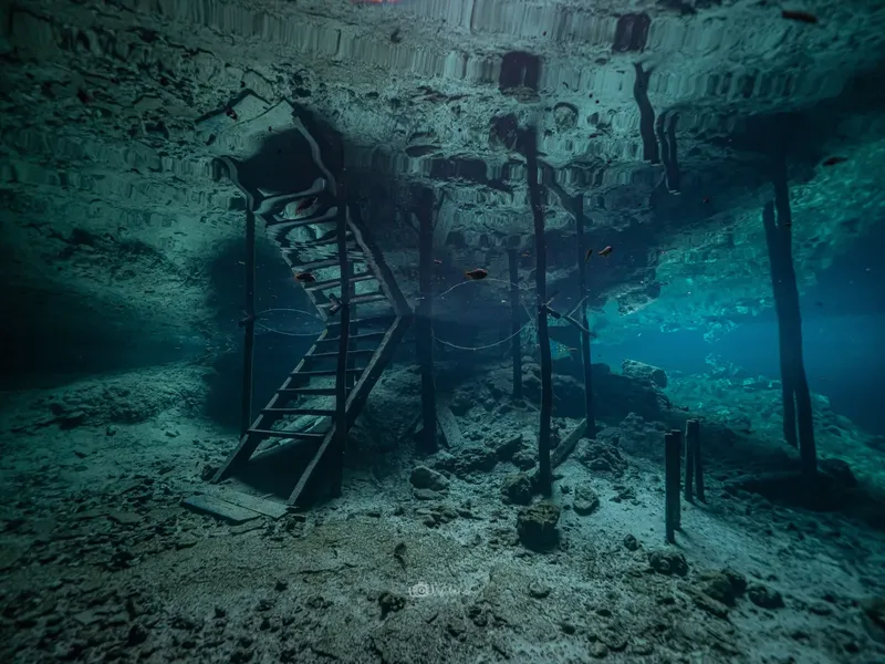 Structure sous-marine avec un escalier, lumière bleutée et sable