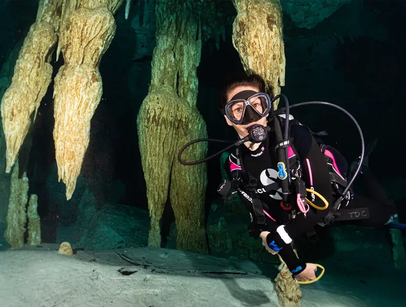 Plongeur explore une grotte sous-marine avec stalactites et visibilité claire