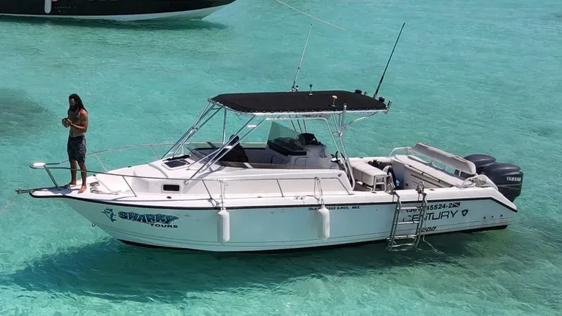 Homme debout sur la proue d'un bateau blanc en mer turquoise