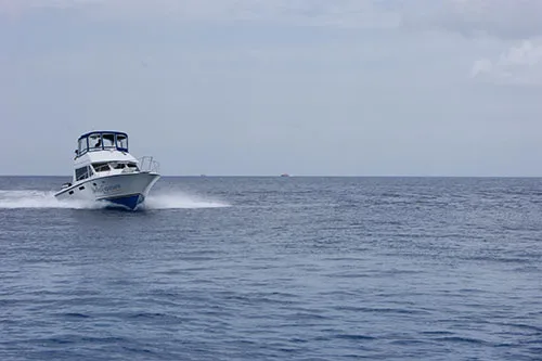 Bateau de plongée blanc naviguant sur une mer calme et grise
