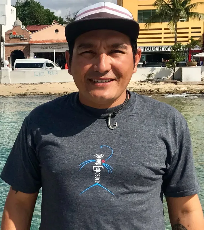 Homme souriant portant un t-shirt gris et une casquette