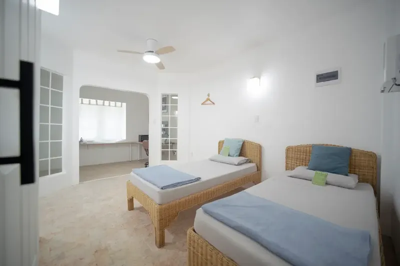 Chambre avec deux lits simples, ventilateur au plafond, décoration sobre