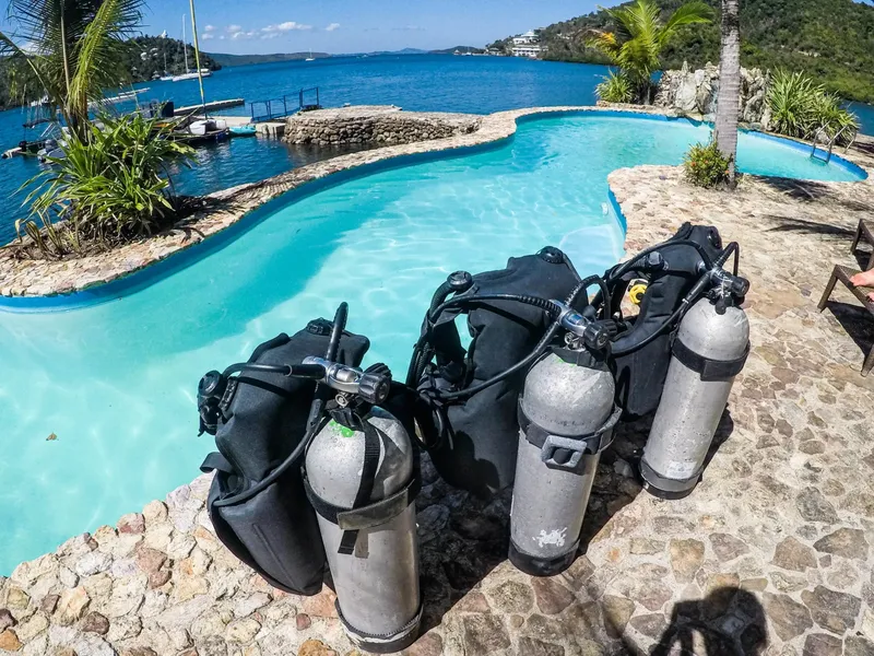Bouteilles de plongée et détendeurs près d'une piscine turquoise et mer