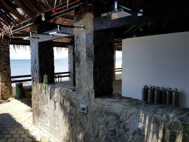 Espace douche extérieur avec bouteilles de plongée et vue sur mer