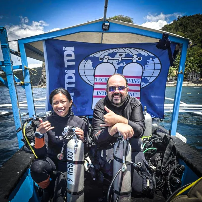 Deux plongeurs souriants à bord d'un bateau avec leur équipement