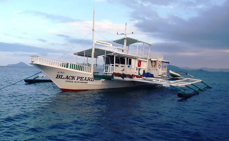 Bateau de plongée blanc avec le nom Black Pearl sur l'eau calme