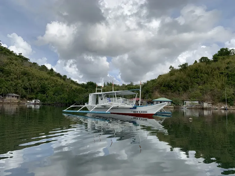 Bateau de plongée amarré dans une baie abritée sous un ciel nuageux