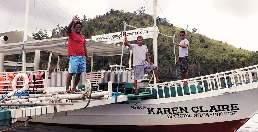 Trois hommes saluent sur le pont d'un bateau de plongée blanc