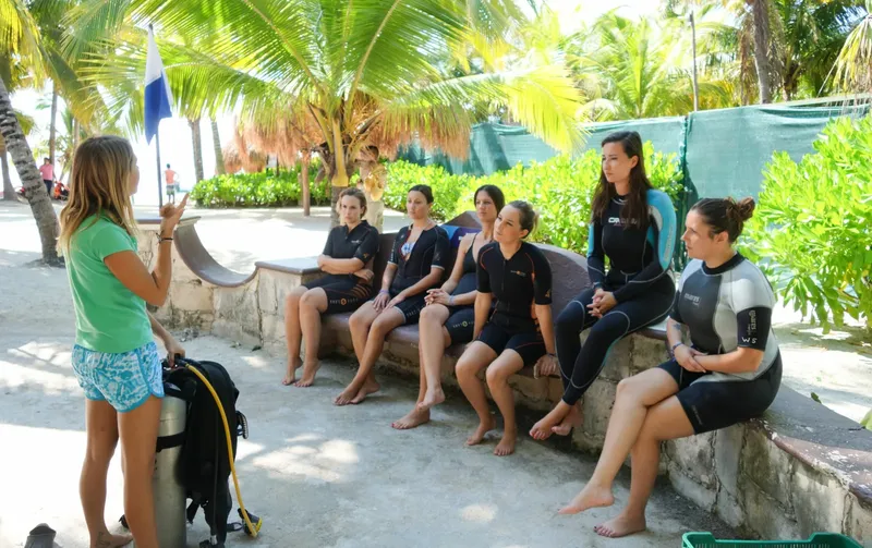 Groupe de personnes en combinaison de plongée écoutent une explication