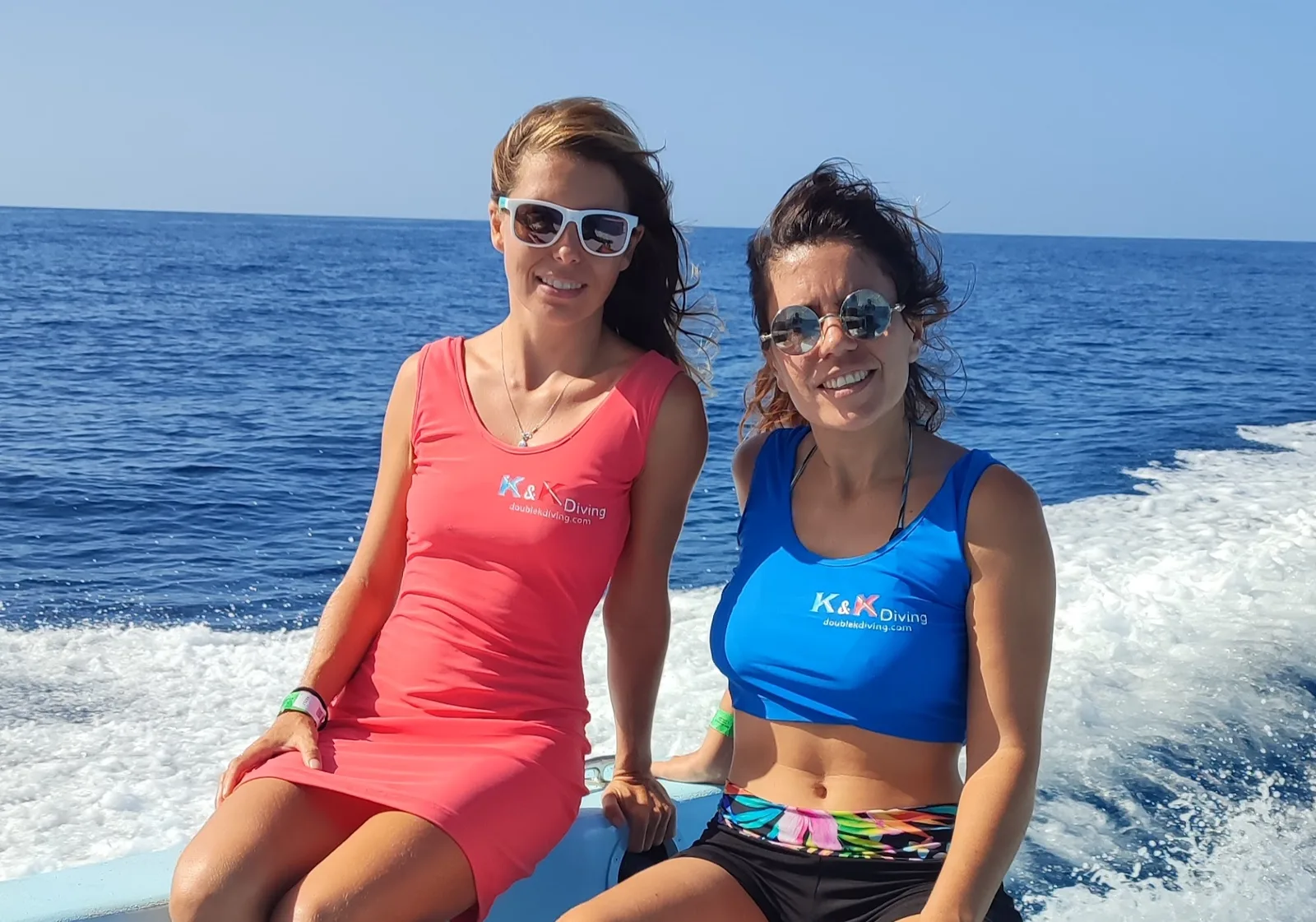 Deux femmes souriantes sur un bateau en mer, lunettes de soleil