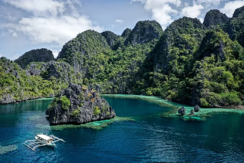 Paysage tropical avec des îles rocheuses et un bateau traditionnel