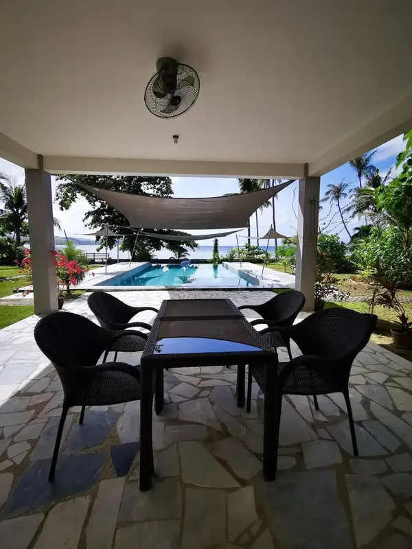 Terrasse ombragée avec mobilier de jardin donnant sur une piscine et la mer