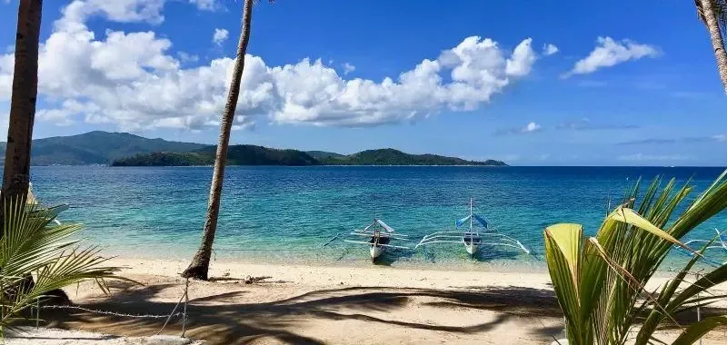 Plage tropicale avec deux bateaux de pêche traditionnels et ciel nuageux