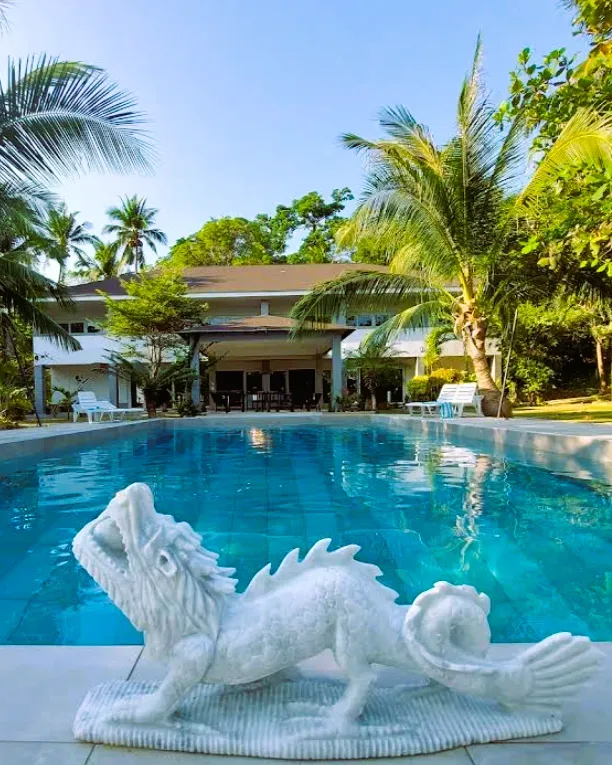 Piscine devant un bâtiment blanc tropical avec une statue de dragon
