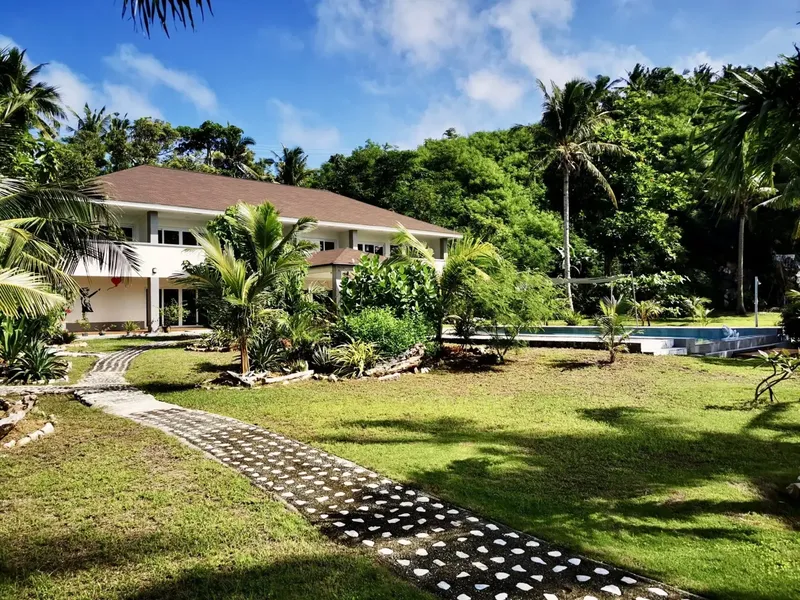 Bâtiment blanc avec toit brun entouré de végétation tropicale luxuriante