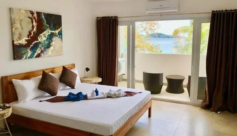 Chambre d'hôtel avec lit fait, vue sur mer et décoration soignée