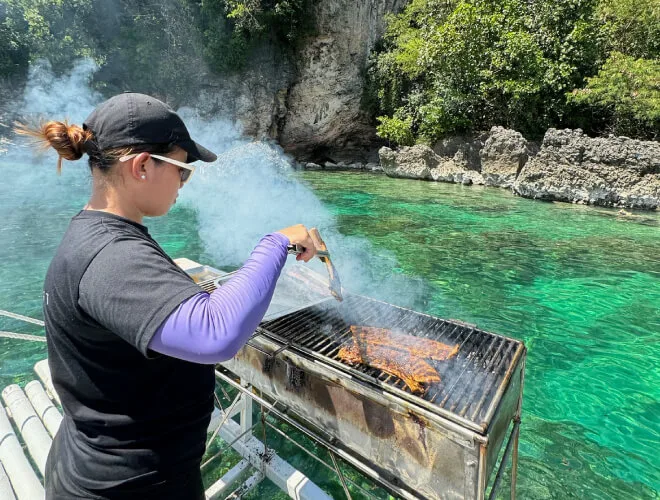 Femme préparant un barbecue sur un bateau au bord de l'eau