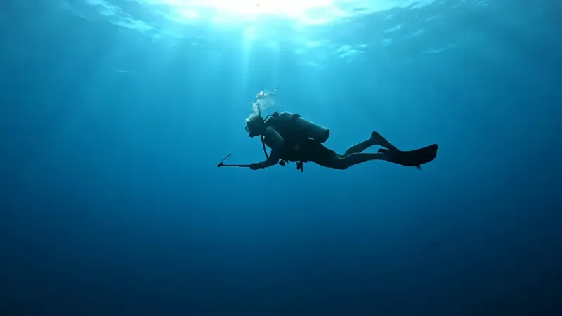 Plongeur en silhouette nageant dans une eau bleue et lumineuse