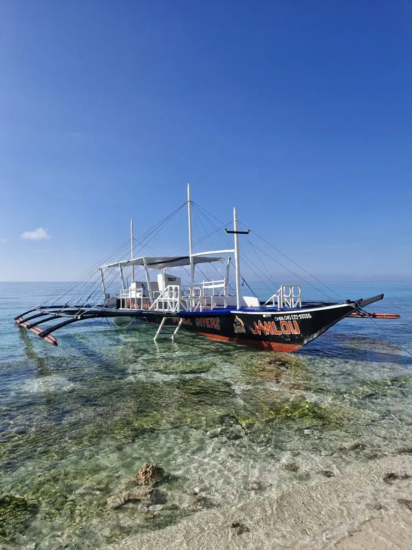 Bateau de plongée traditionnel amarré dans une eau turquoise claire