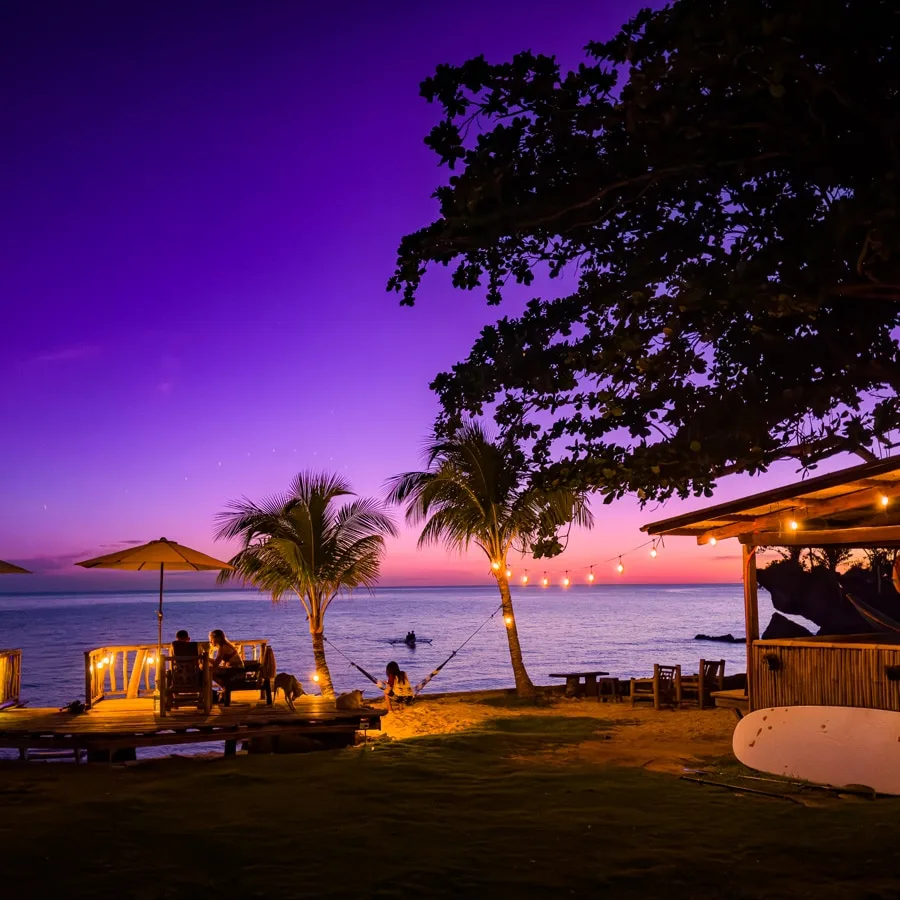 Personnes assises sur une terrasse au bord de la mer au coucher du soleil