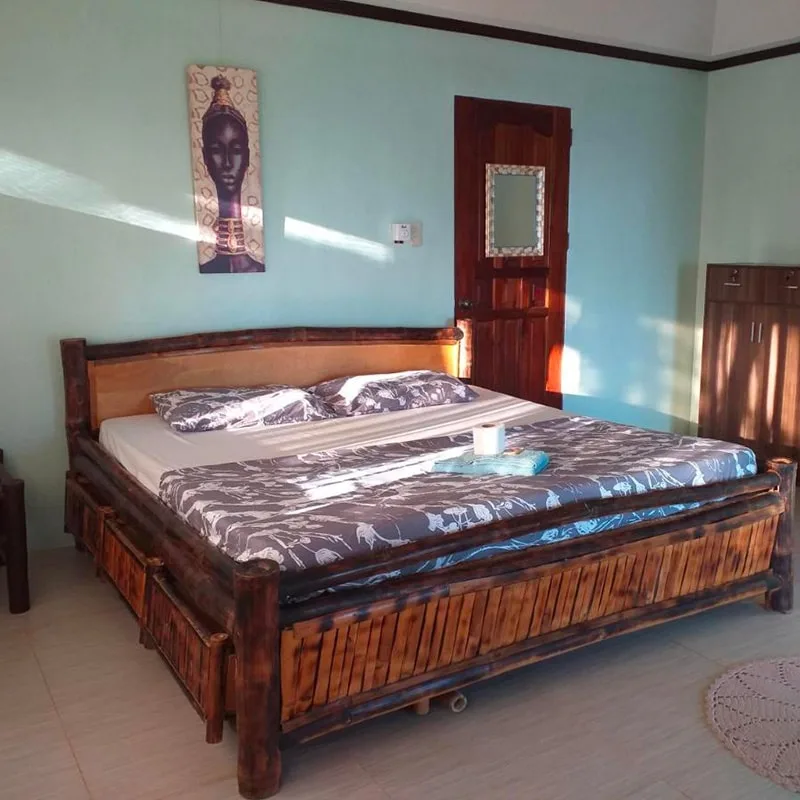 Chambre avec grand lit en bois, décoration murale et lumière naturelle