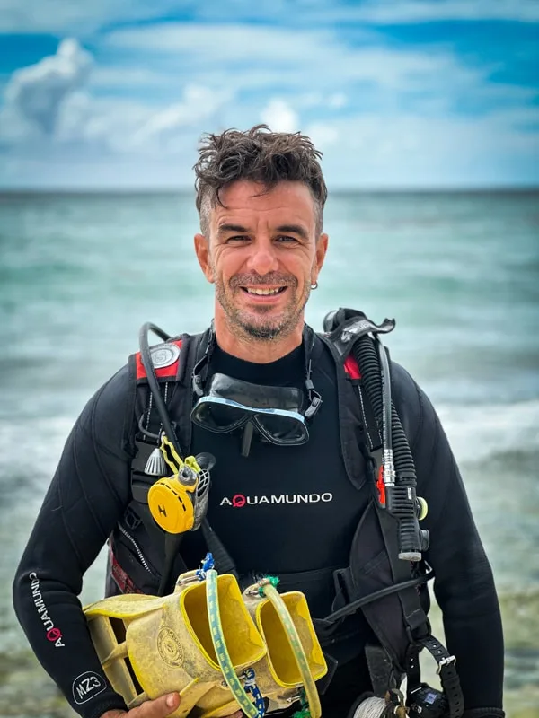 Plongeur souriant avec équipement complet devant la mer bleue