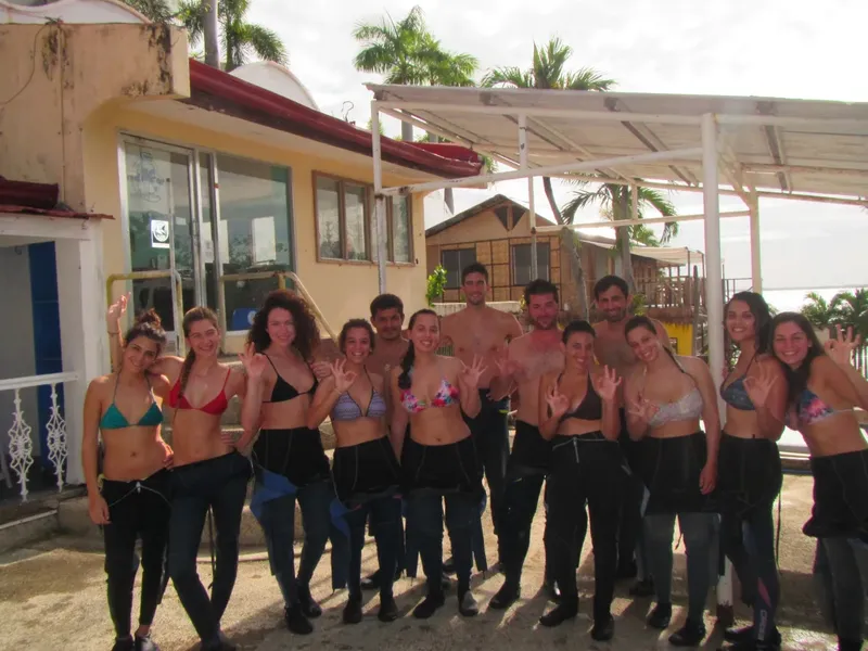 Groupe de personnes souriantes en tenue de plongée devant un bâtiment