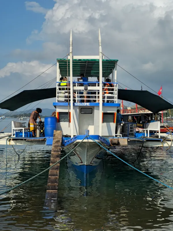 Bateau de plongée amarré avec des personnes à bord et un auvent
