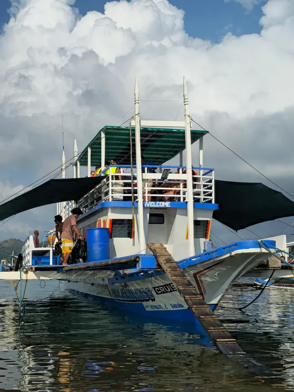 Bateau de plongée bleu et blanc amarré avec des passagers à bord