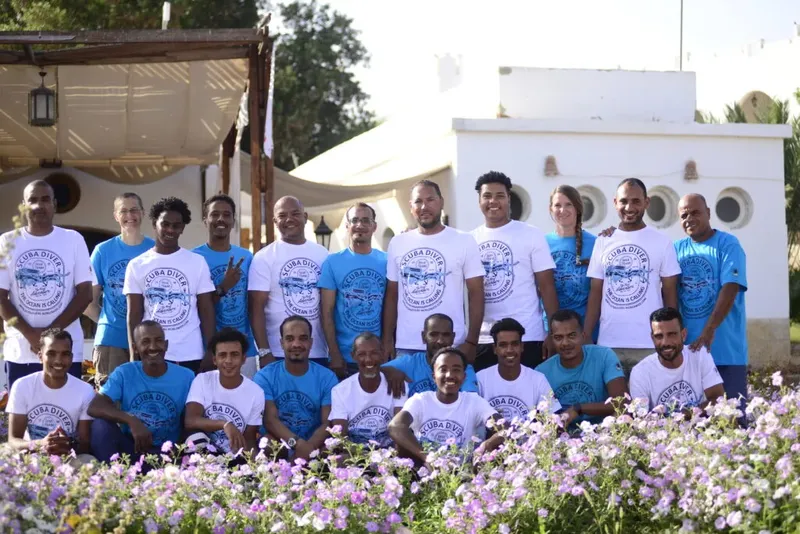 Groupe de personnes souriantes portant des t-shirts devant un bâtiment