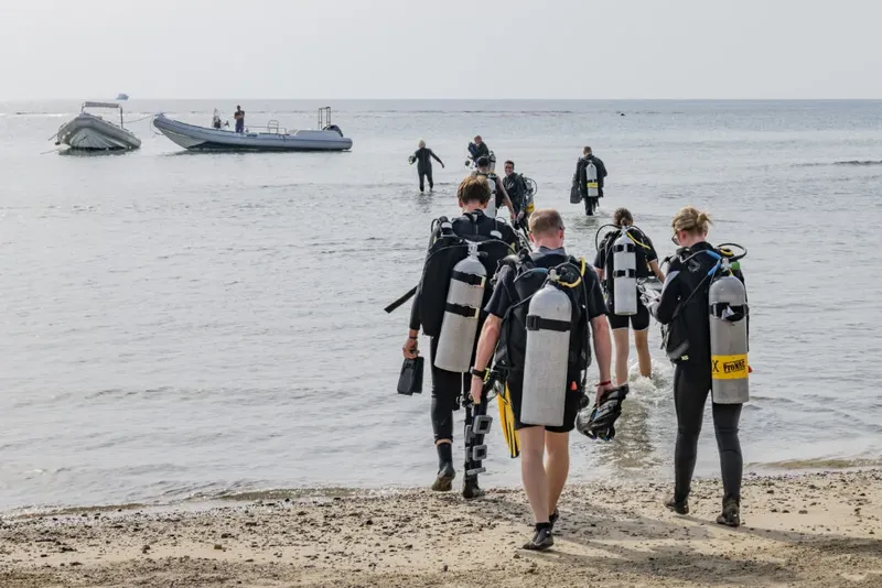 Plongée : groupe de personnes équipées marchant dans l'eau avec bouteilles