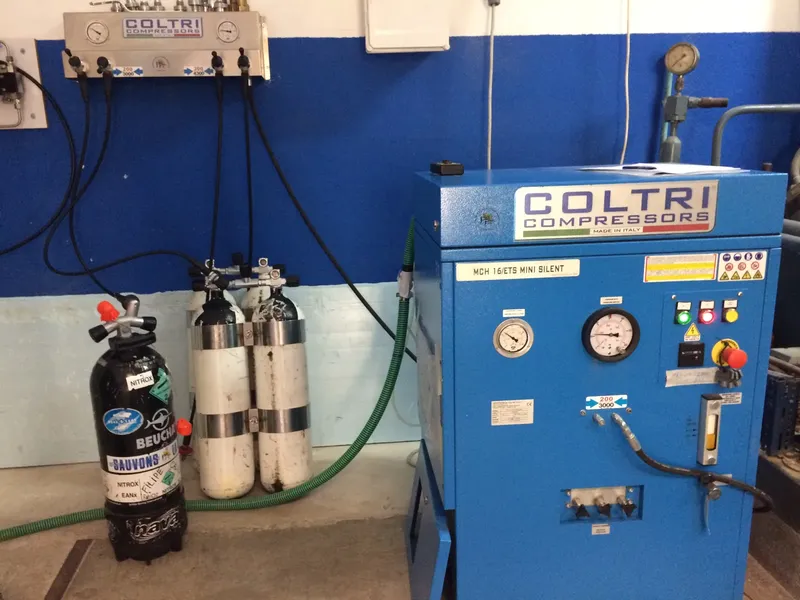 Compresseur Coltri bleu, bouteilles de plongée et manomètres dans un local