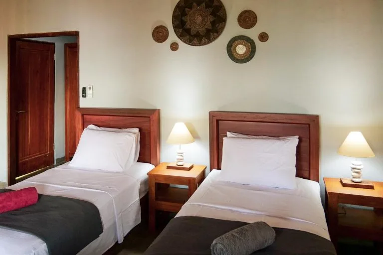 Chambre avec deux lits simples, décoration murale et éclairage d'ambiance
