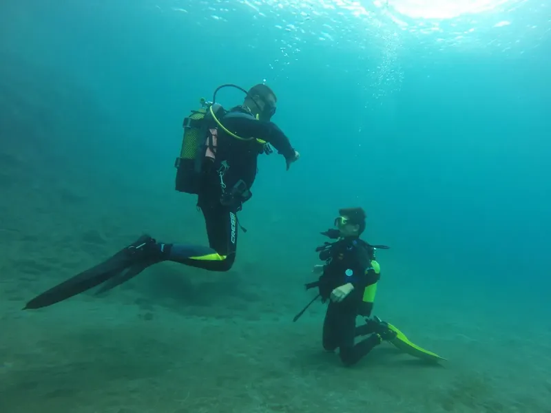Deux plongeurs en combinaison explorent les fonds marins sablonneux