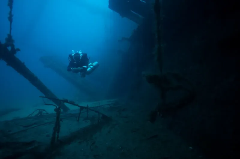Plongeur explorant l'épave d'un navire sous-marin, lumière bleutée