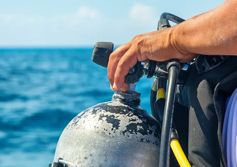 Main manipulant un détendeur sur une bouteille de plongée en mer