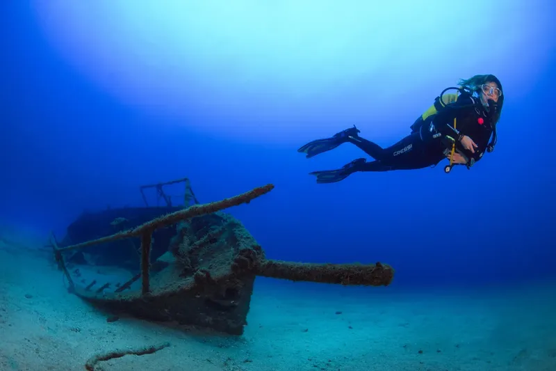 Plongeur explore une épave sous-marine dans une eau bleue claire