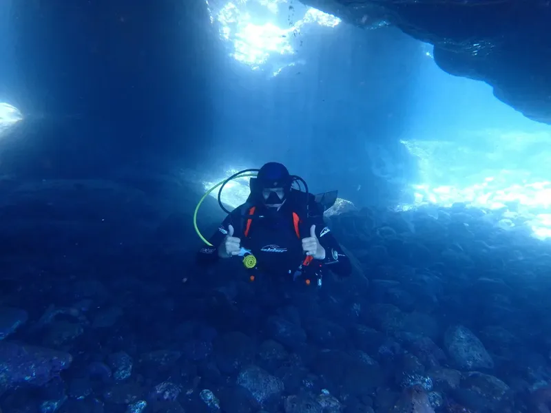 Plongeur sous l'eau, pouce levé, exploration d'une grotte marine bleue