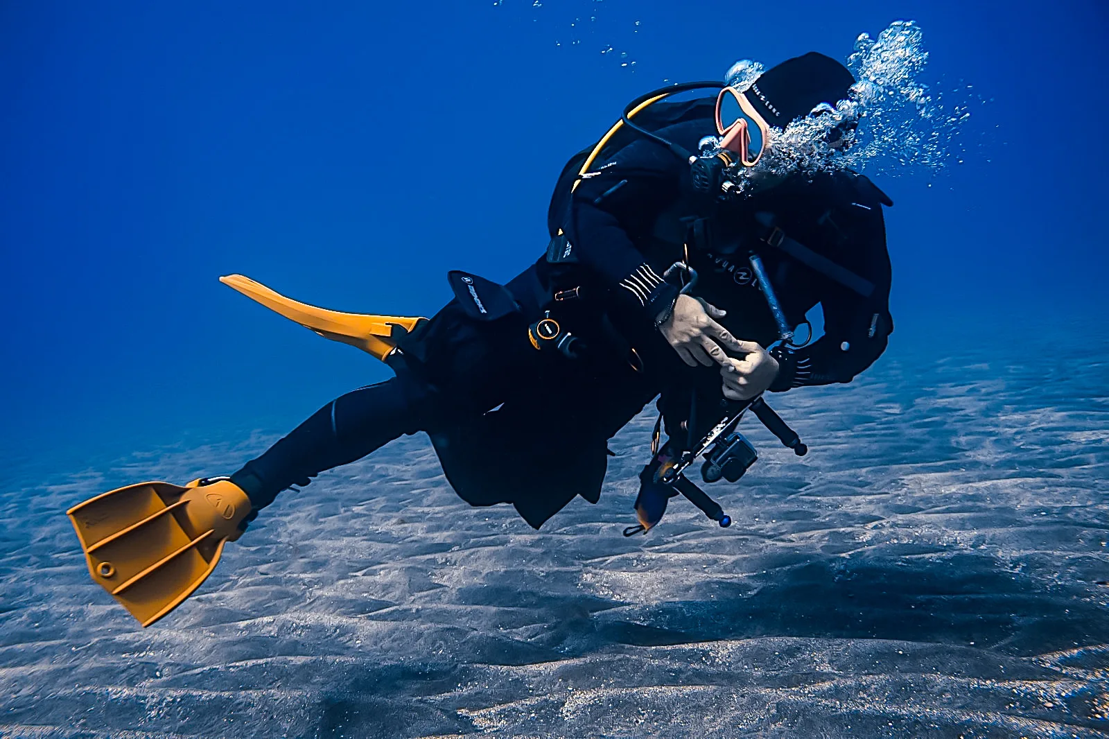 Plongeur en combinaison noire nageant dans une eau bleue claire