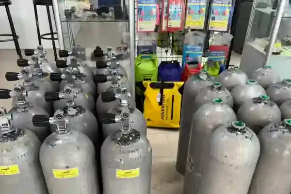Nombreuses bouteilles de plongée alignées dans un local avec du matériel
